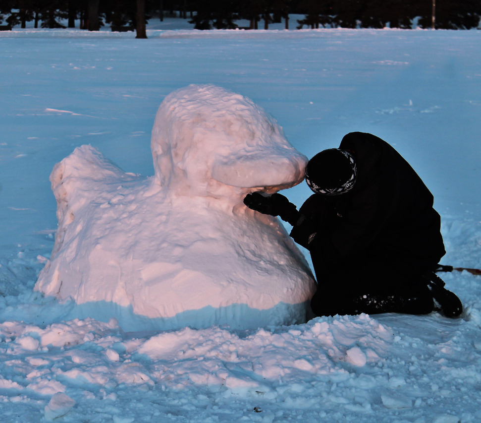 an image of Juan Camilo outdoors during the winter. He appears working on a snow sculpture of a rubber ducky.